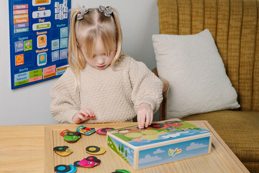 Child playing with a colorful puzzle on a table in a home setting.