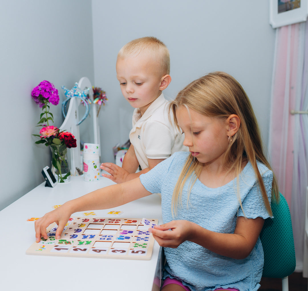 Two children playing with a puzzle game that includes one wooden board and colorful tiles that fit into it.